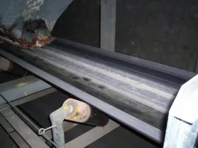 Belt mistracking due to material spillage and lack of conveyor skirting.
